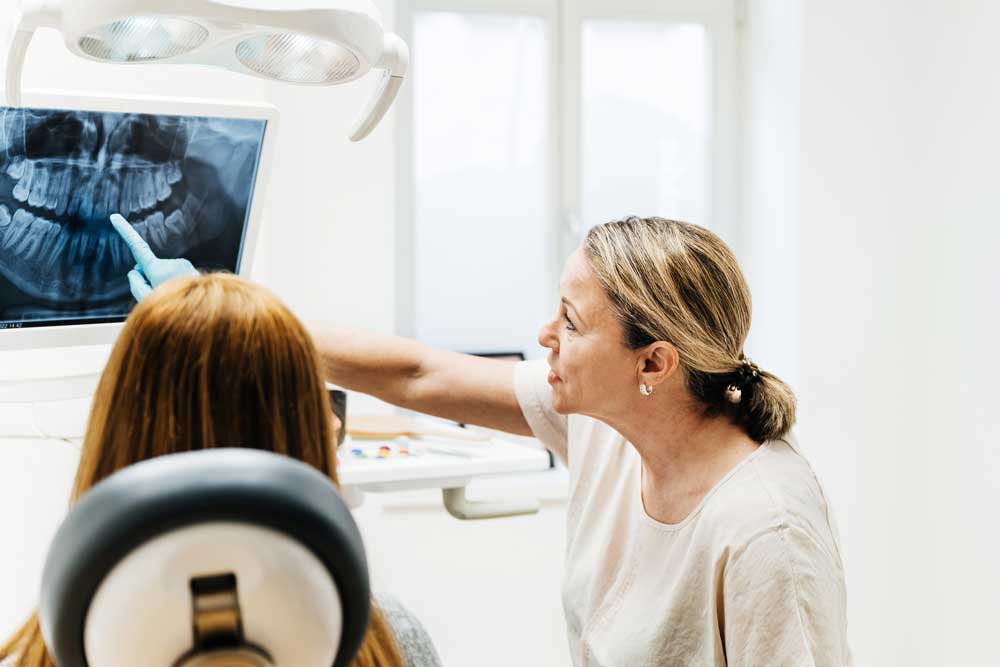 Tandläkare visar bild på röntgen av tänder