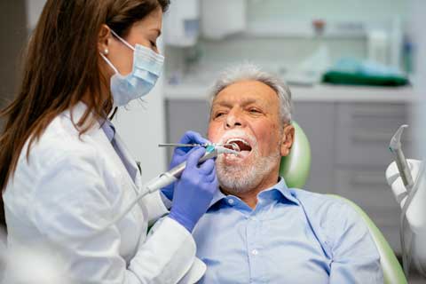 Tandläkare utför undersökning på en äldre man